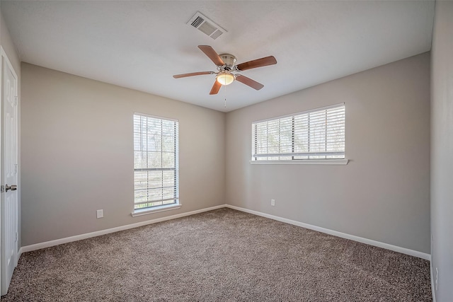 carpeted empty room with a healthy amount of sunlight, visible vents, and baseboards