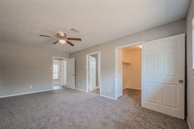 unfurnished bedroom with a ceiling fan, baseboards, visible vents, carpet floors, and a spacious closet