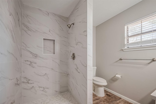 bathroom featuring a marble finish shower, baseboards, toilet, and wood finished floors