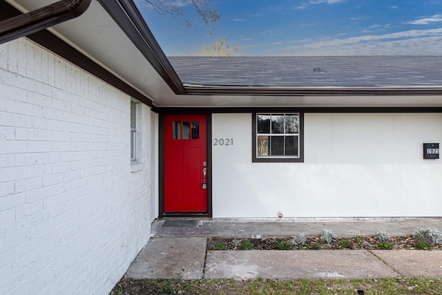 doorway to property featuring a shingled roof