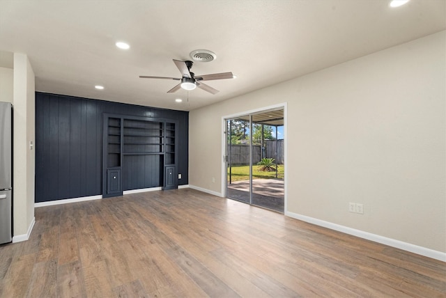 unfurnished bedroom with visible vents, wood finished floors, baseboards, and access to exterior