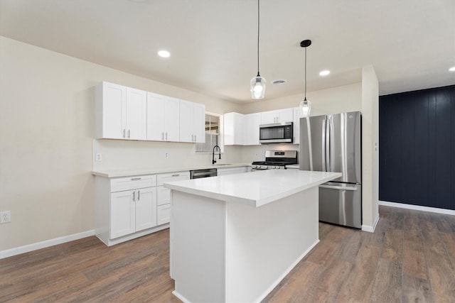 kitchen with a sink, a kitchen island, dark wood-style floors, white cabinetry, and stainless steel appliances