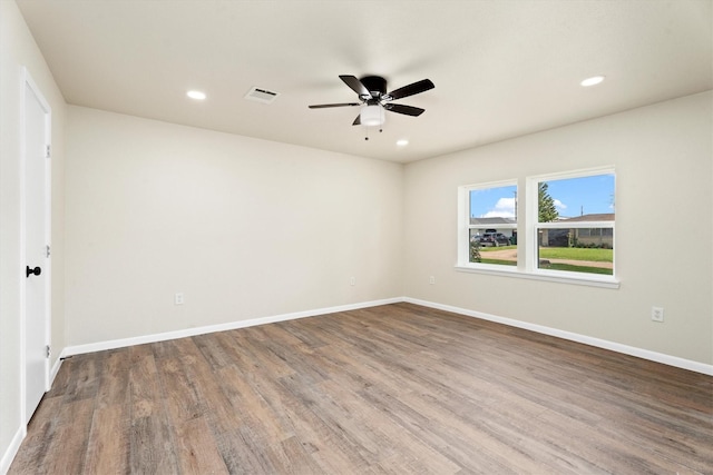 unfurnished room featuring recessed lighting, wood finished floors, visible vents, and baseboards