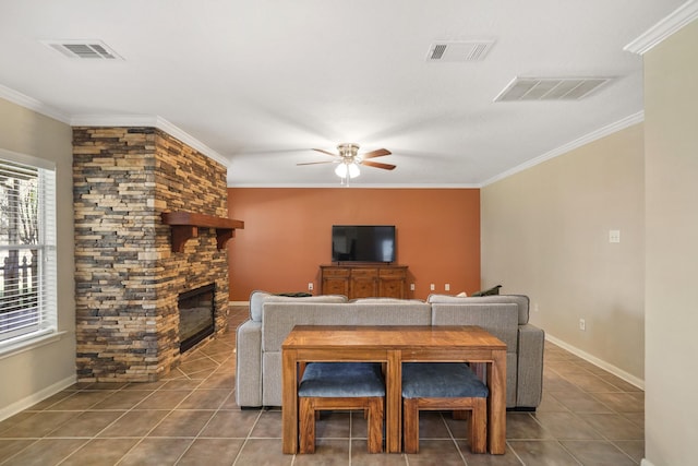 dining space with tile patterned flooring, visible vents, a stone fireplace, and ornamental molding