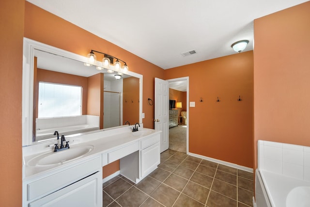 ensuite bathroom with a sink, visible vents, a garden tub, and tile patterned flooring