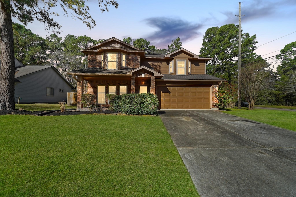 view of front of property featuring a garage, driveway, brick siding, and a front yard