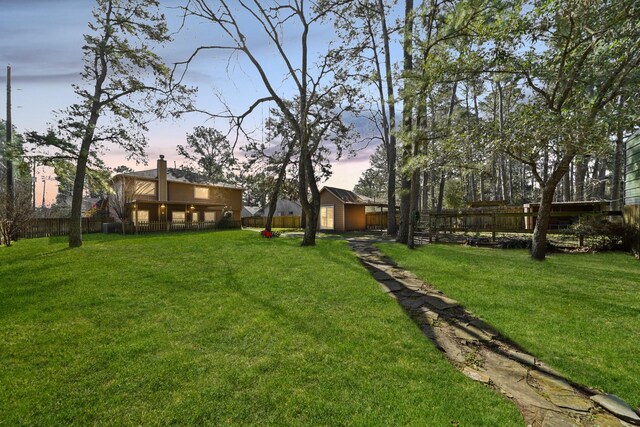 yard at dusk with an outbuilding and fence