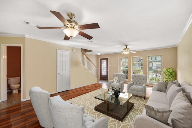 living room featuring plenty of natural light, stairs, visible vents, and wood finished floors