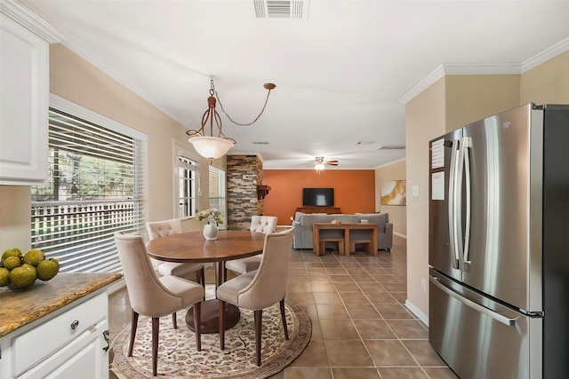 dining area featuring tile patterned flooring, visible vents, crown molding, baseboards, and a ceiling fan