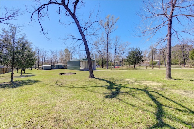 view of yard featuring an outbuilding, a storage shed, and fence