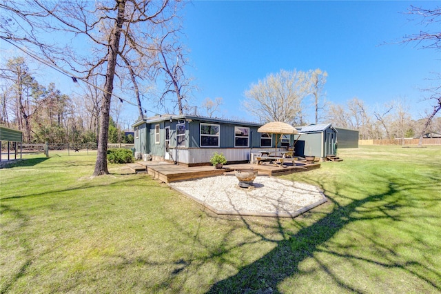 rear view of house featuring a wooden deck, a lawn, an outdoor structure, and fence