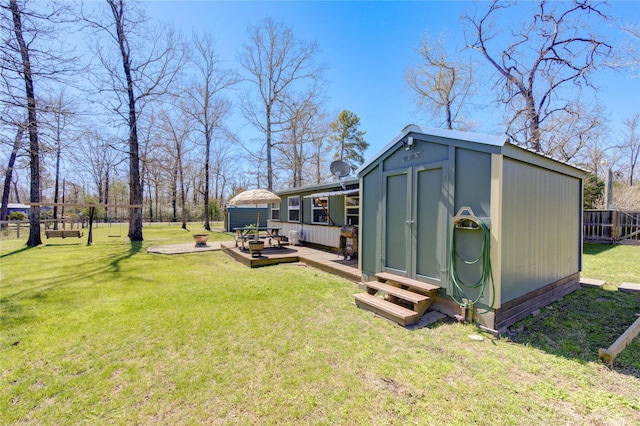 view of yard featuring a deck, an outbuilding, and fence