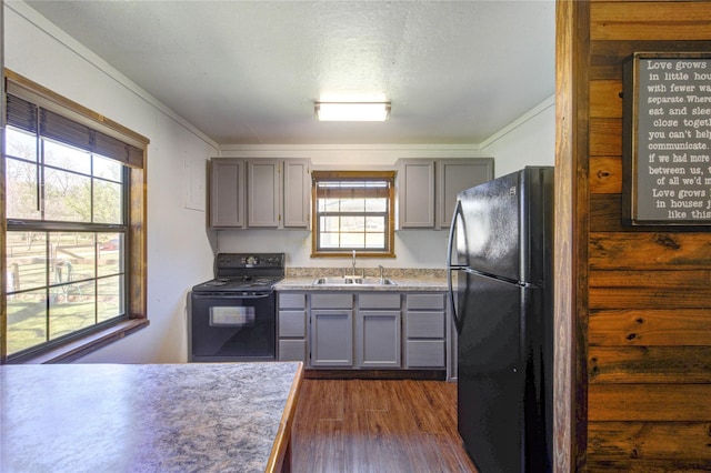 kitchen with gray cabinetry, dark wood finished floors, ornamental molding, black appliances, and a sink