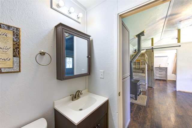 bathroom with toilet, hardwood / wood-style floors, vanity, and a textured wall