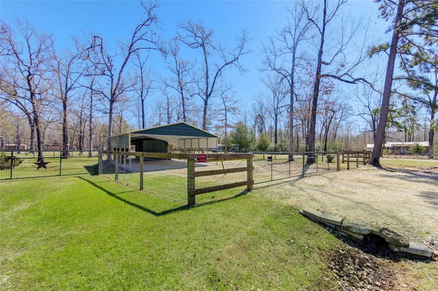 view of yard with an outbuilding, fence, driveway, and a carport