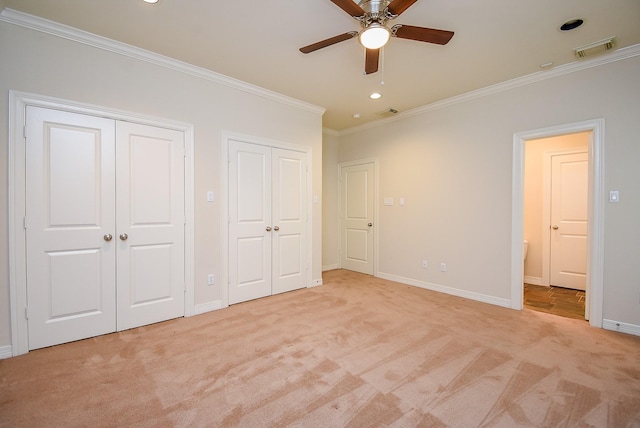 unfurnished bedroom with light carpet, visible vents, two closets, and crown molding