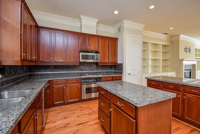 kitchen with tasteful backsplash, stainless steel appliances, light wood-type flooring, a center island, and crown molding
