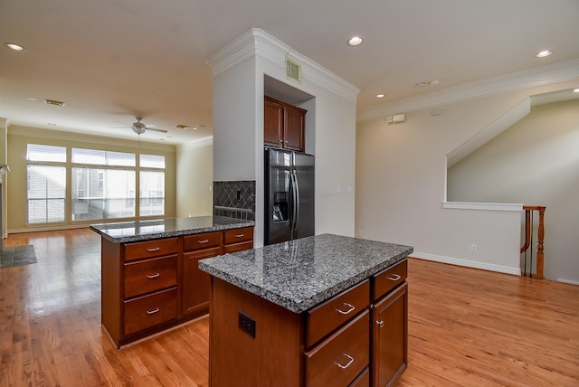 kitchen featuring light wood-type flooring, visible vents, black fridge with ice dispenser, a center island, and crown molding