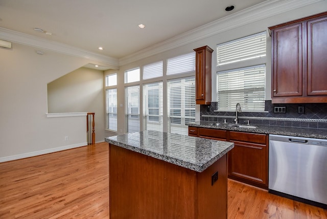 kitchen featuring dishwasher, a center island, crown molding, and a sink