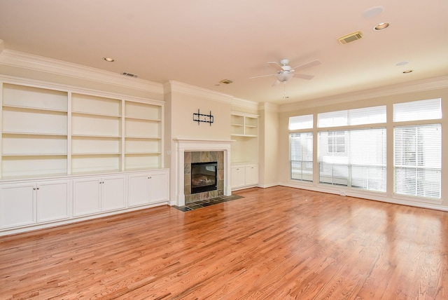 unfurnished living room featuring visible vents, light wood-style flooring, a tile fireplace, and crown molding