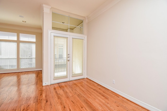 empty room featuring light wood-style floors, french doors, crown molding, and baseboards