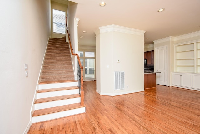 staircase featuring visible vents, ornamental molding, baseboards, and wood finished floors