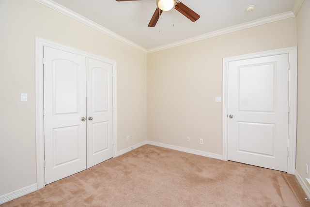 unfurnished bedroom with light carpet, a closet, crown molding, baseboards, and ceiling fan