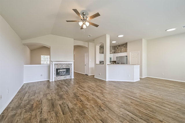 unfurnished living room with baseboards, lofted ceiling, ceiling fan, and wood finished floors