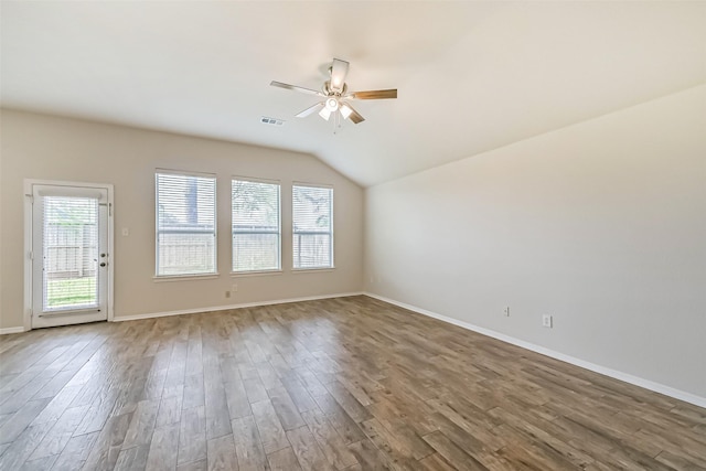 spare room with wood finished floors, baseboards, visible vents, ceiling fan, and vaulted ceiling