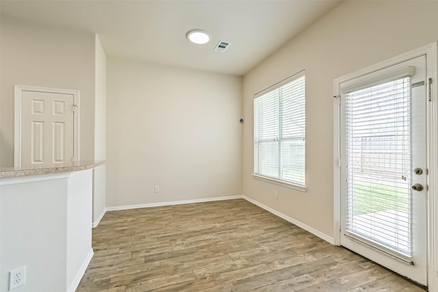 empty room with light wood-style flooring, visible vents, and baseboards