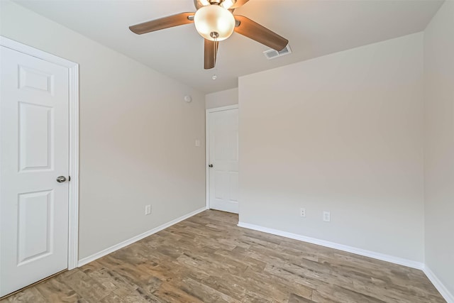 empty room with baseboards, wood finished floors, visible vents, and ceiling fan