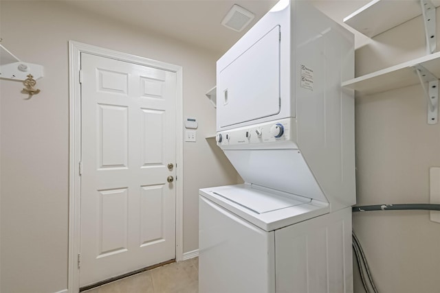 washroom with light tile patterned floors, stacked washer / dryer, laundry area, and visible vents