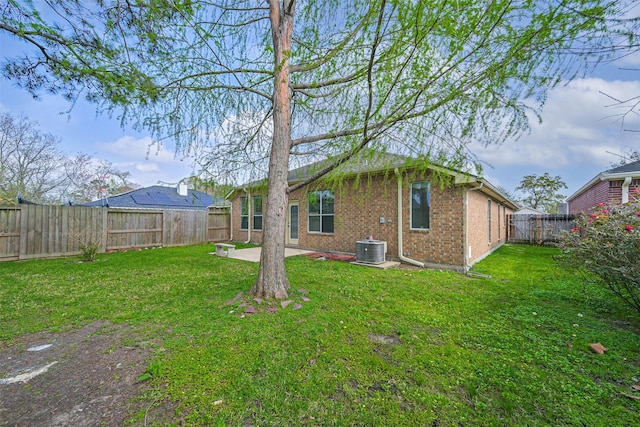 rear view of property with a yard, a patio, brick siding, and a fenced backyard