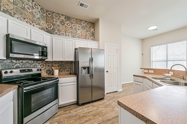 kitchen featuring a sink, white cabinets, visible vents, and stainless steel appliances