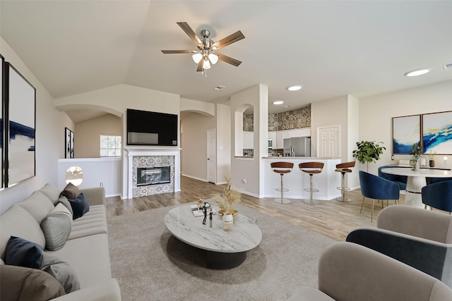 living room featuring light wood-style flooring, recessed lighting, arched walkways, ceiling fan, and vaulted ceiling