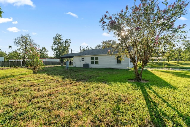 rear view of house featuring a lawn, cooling unit, and fence