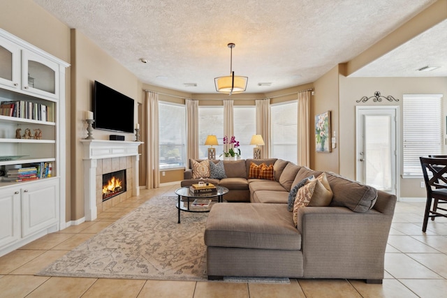 living area with a tiled fireplace, light tile patterned floors, visible vents, and a textured ceiling