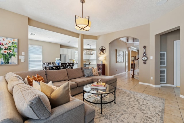 living area with light tile patterned floors, baseboards, arched walkways, and a textured ceiling