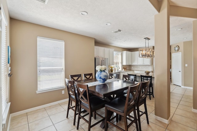 dining area with light tile patterned floors, baseboards, visible vents, and a chandelier