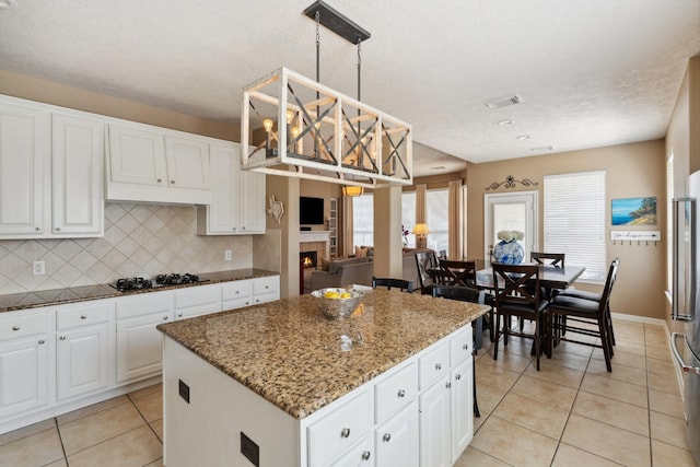 kitchen with visible vents, stone countertops, gas cooktop, tasteful backsplash, and light tile patterned floors