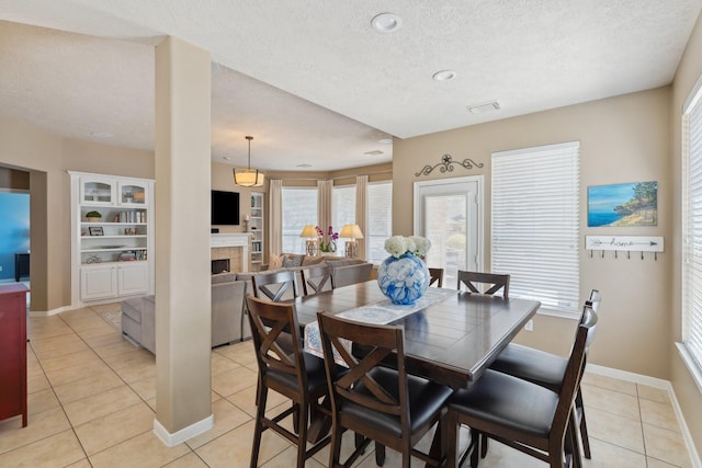 dining room with baseboards, visible vents, light tile patterned flooring, a tile fireplace, and a textured ceiling