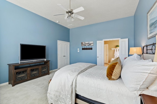 carpeted bedroom with a closet, baseboards, ceiling fan, and a towering ceiling