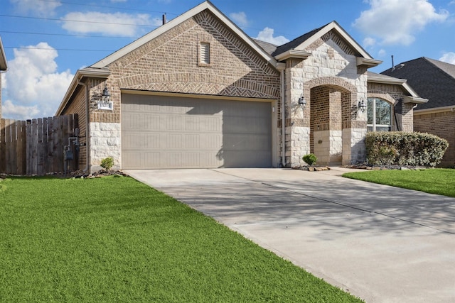 french country inspired facade featuring fence, driveway, an attached garage, stone siding, and brick siding