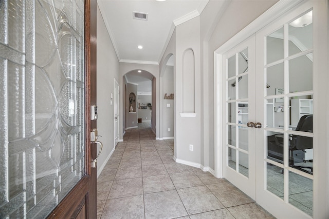 entrance foyer with light tile patterned floors, visible vents, arched walkways, french doors, and crown molding