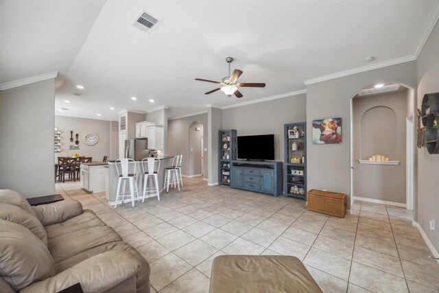 living area with visible vents, baseboards, light tile patterned floors, arched walkways, and a ceiling fan