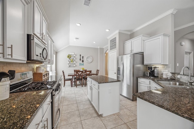 kitchen with visible vents, a kitchen island, light tile patterned floors, appliances with stainless steel finishes, and a sink