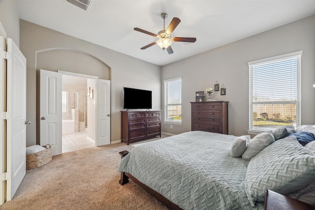 carpeted bedroom with ceiling fan, visible vents, baseboards, and connected bathroom