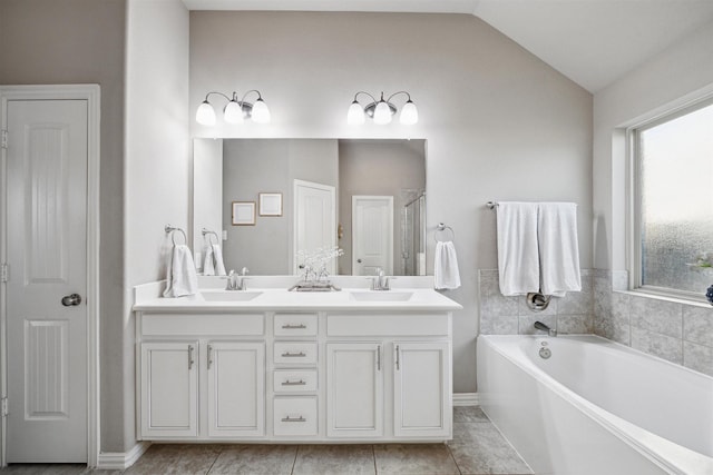 bathroom with vaulted ceiling, a garden tub, double vanity, and a sink