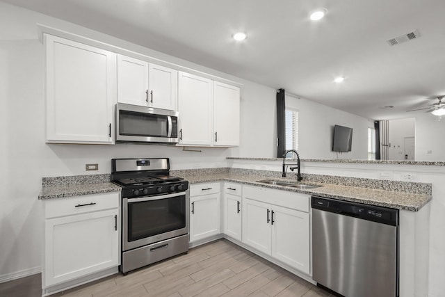 kitchen featuring visible vents, a peninsula, a sink, white cabinets, and appliances with stainless steel finishes