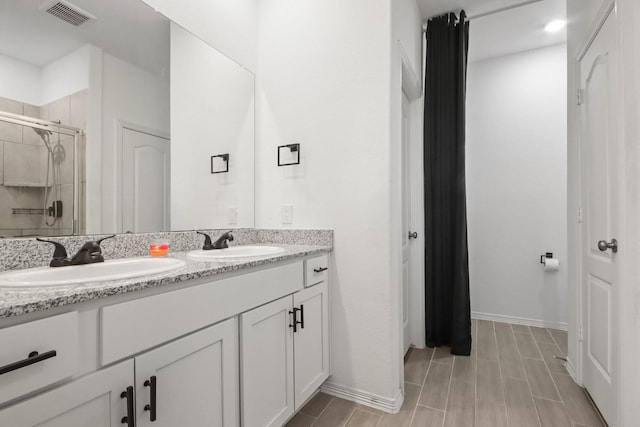 full bath with a shower stall, double vanity, visible vents, and a sink